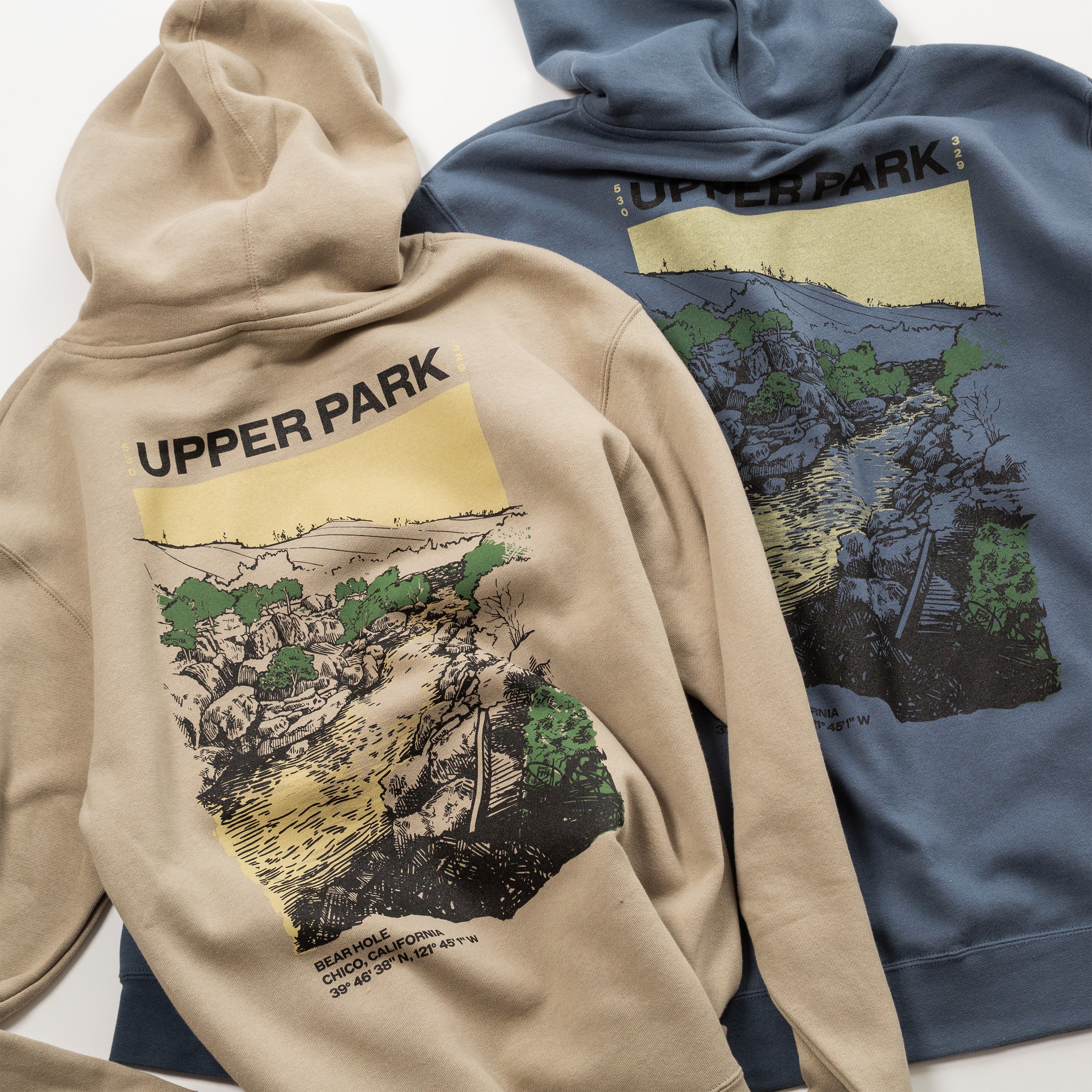 Two hoodies, one beige and one blue, with 'Upper Park' branding and nature-themed designs on the back.