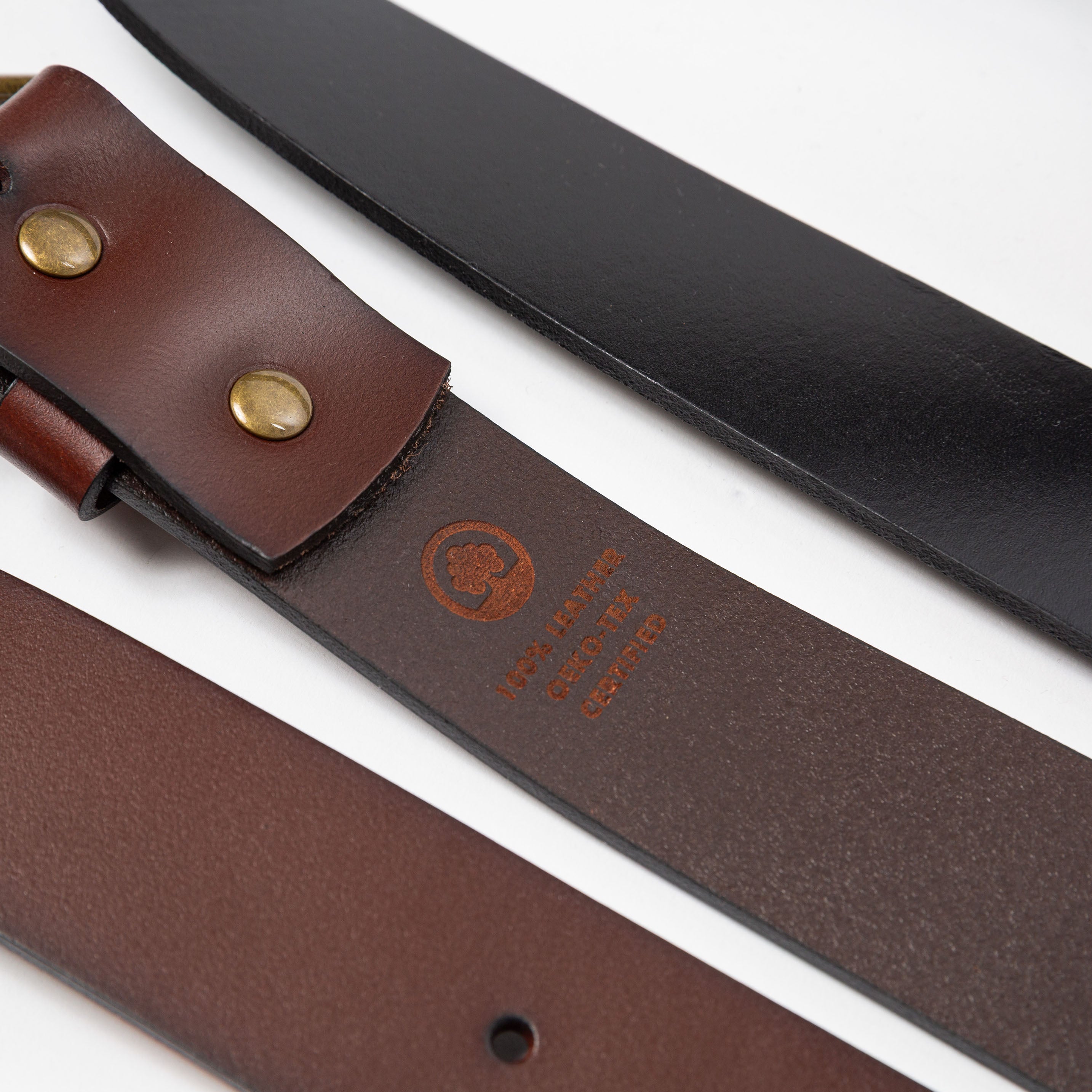 a close up of two leather belts showing the underside and top side textures with an etching burned into the underside showing 100% leather - Upper Park basic leather belt