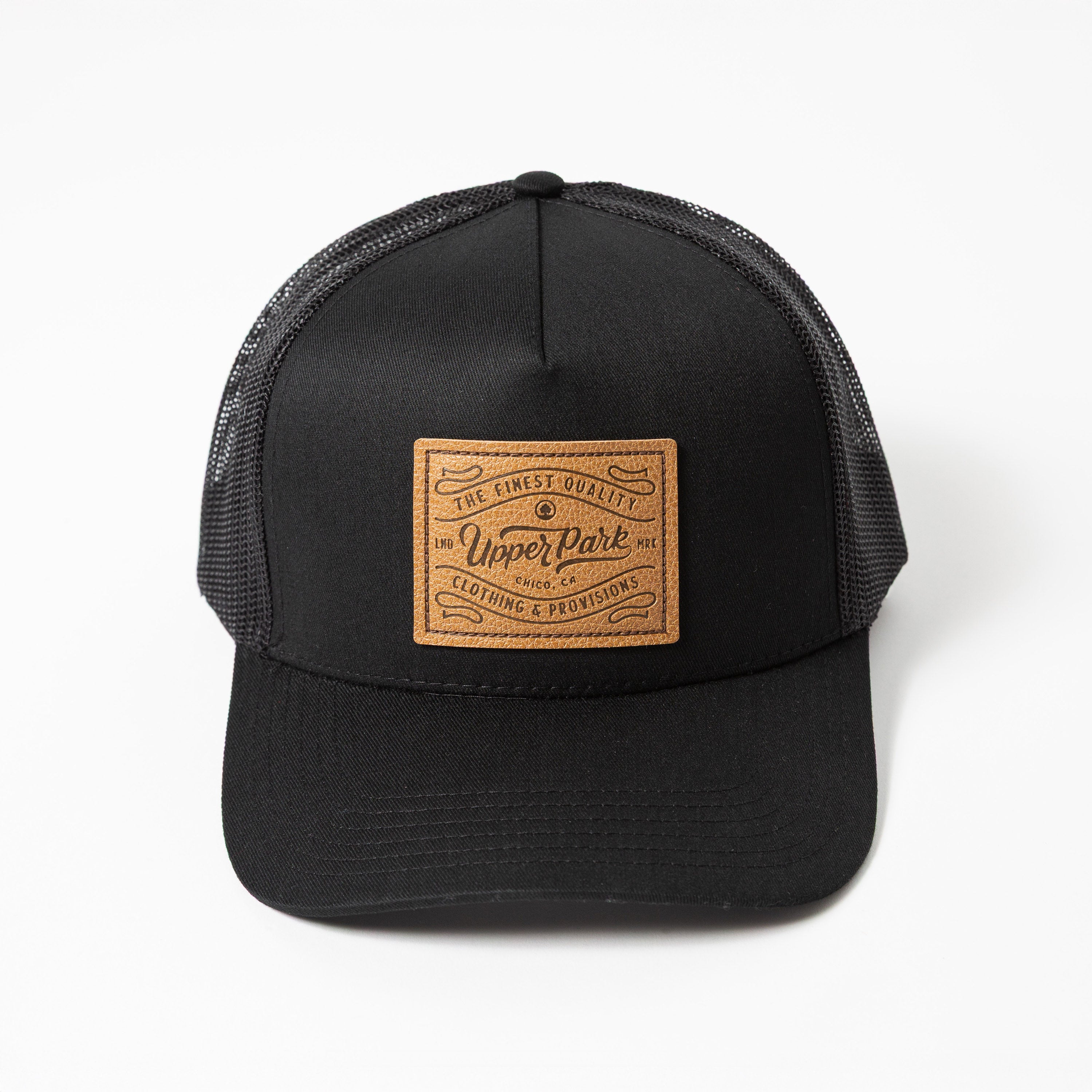 Upper Park Pro Label 5 Panel Trucker Hat - Black trucker cap with a leather patch on a white background