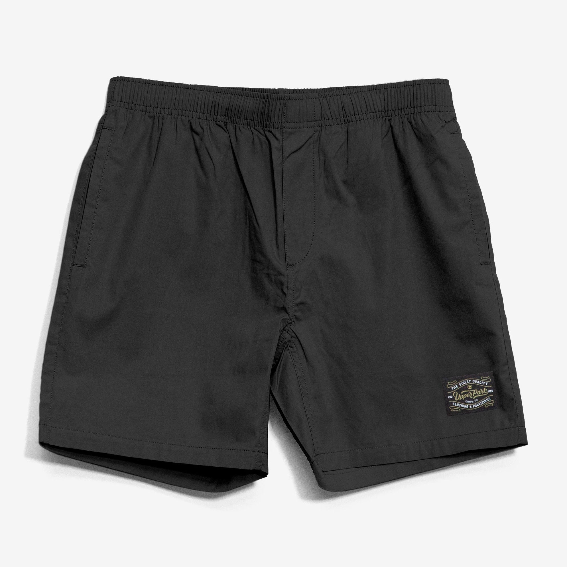 A pair of black beach shorts with a drawstring waistband and a small label on the right leg.