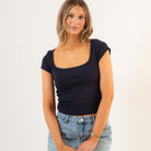 Woman wearing a navy blue top and blue jeans on a white background