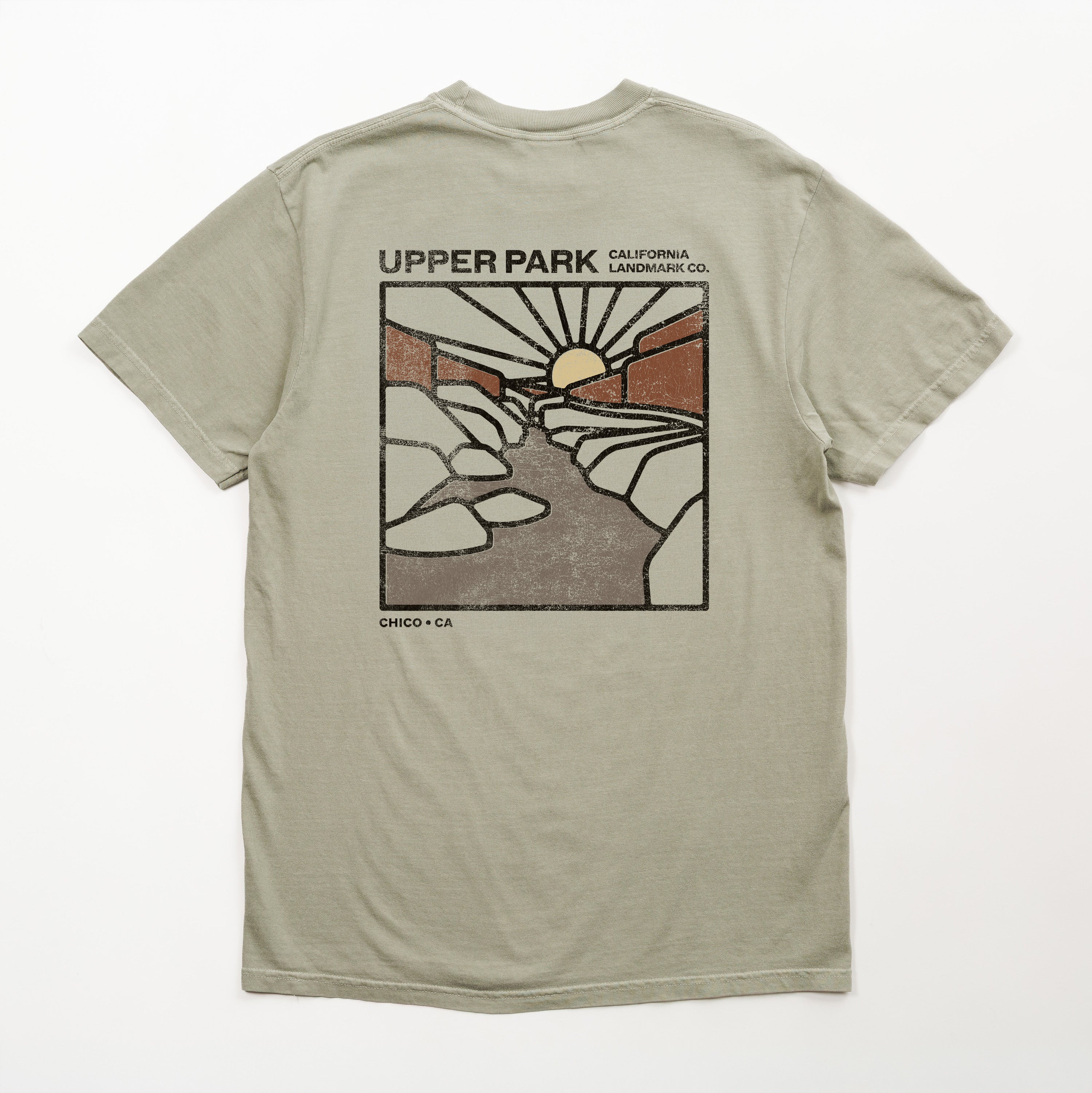 A light sage green t-shirt shown from the back, featuring a large vintage-style graphic print of 'Upper Park, California, Chico, Ca' with a sun, rocks, and a river.