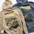 Two hoodies, one beige and one blue, with 'Upper Park' branding and nature-themed designs on the back.