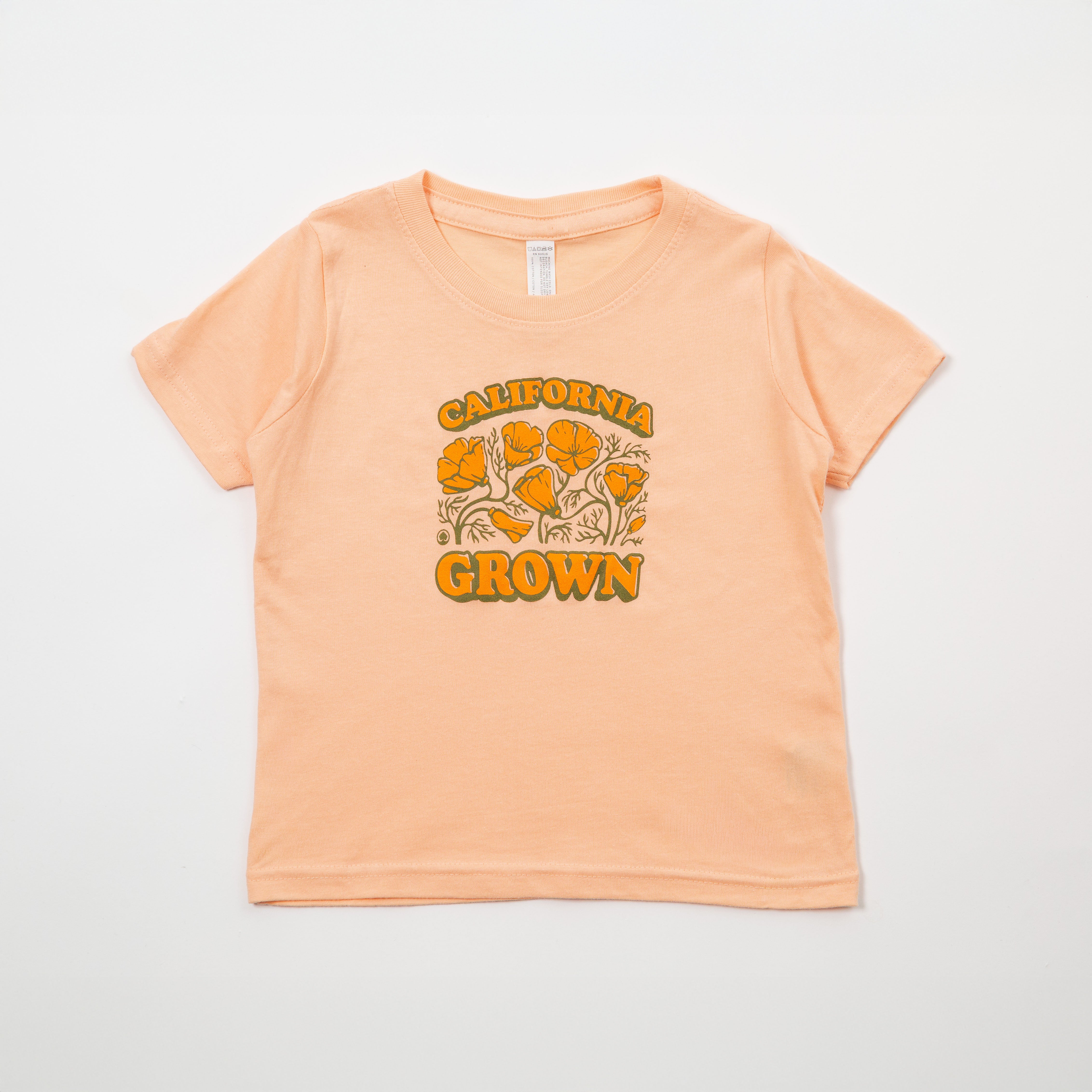 Peach-colored t-shirt with 'California Grown' text and floral design on a light gray background