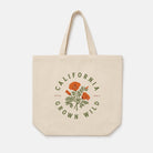 A natural canvas tote bag with a printed graphic featuring orange poppies and green leaves, surrounded by the text 'CALIFORNIA GROWN WILD' in green. The bag is shown against a plain, light gray background.