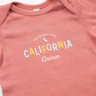 Pink baby onesie with 'California Grown' text on a plain background - Upper Park Baby Onesie California Collection