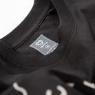 Upper Park Bay Waves Organic Cotton Long Sleeve shirt - Close-up of a black garment with a label on a white background