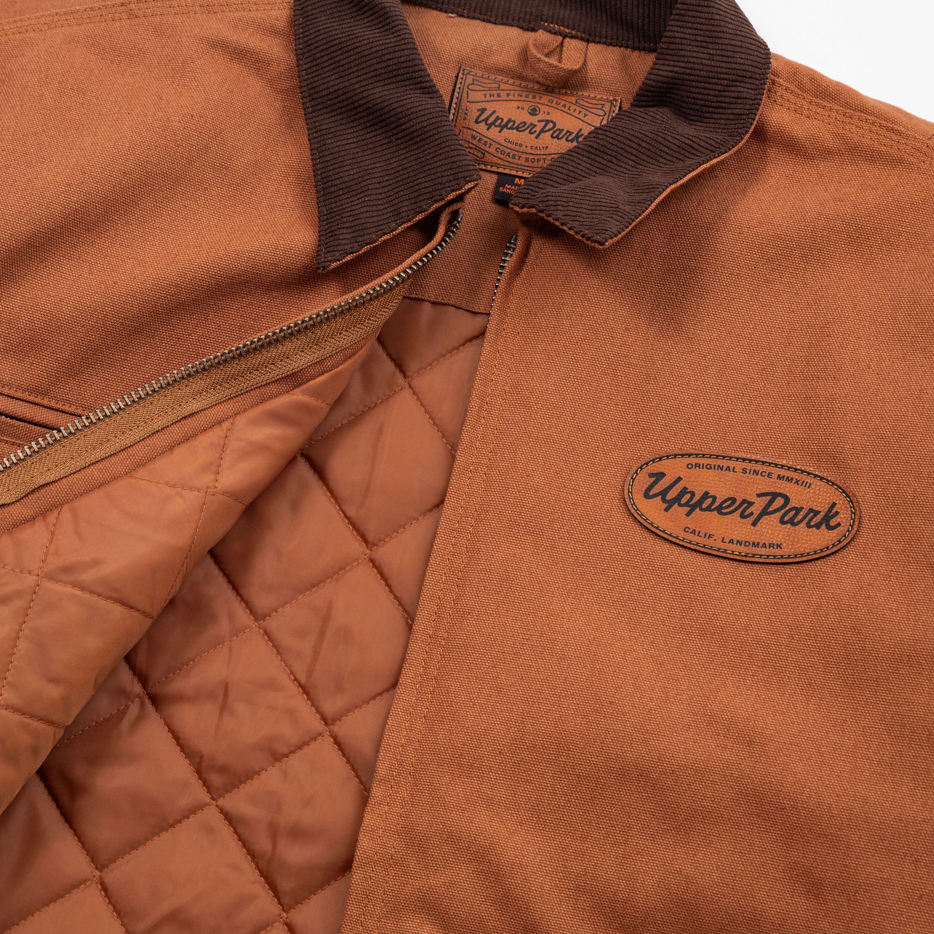 Brown jacket with quilted design and Upper Park logo on a white background - Cultivators Upper Park Barn Jacket