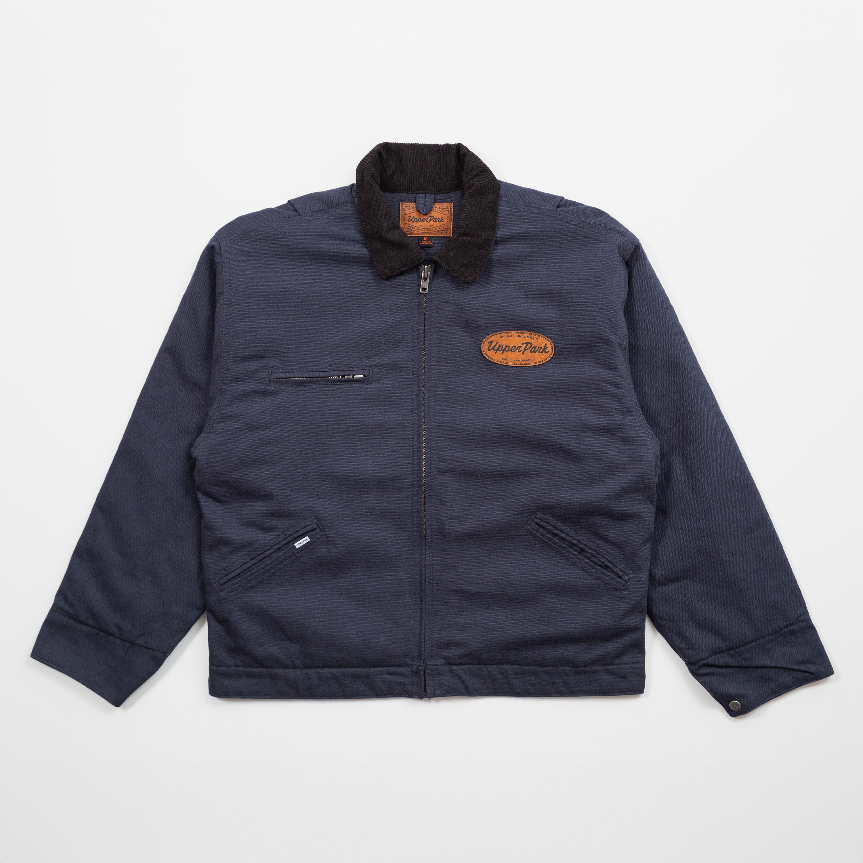 Navy jacket with a brown leather patch on a light gray background - Cultivators Upper Park Barn Jacket