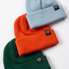 Three beanie hats in green, orange, and blue with a brand logo on a white background