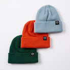 Three beanie hats in green, orange, and blue with a brand logo on a white background