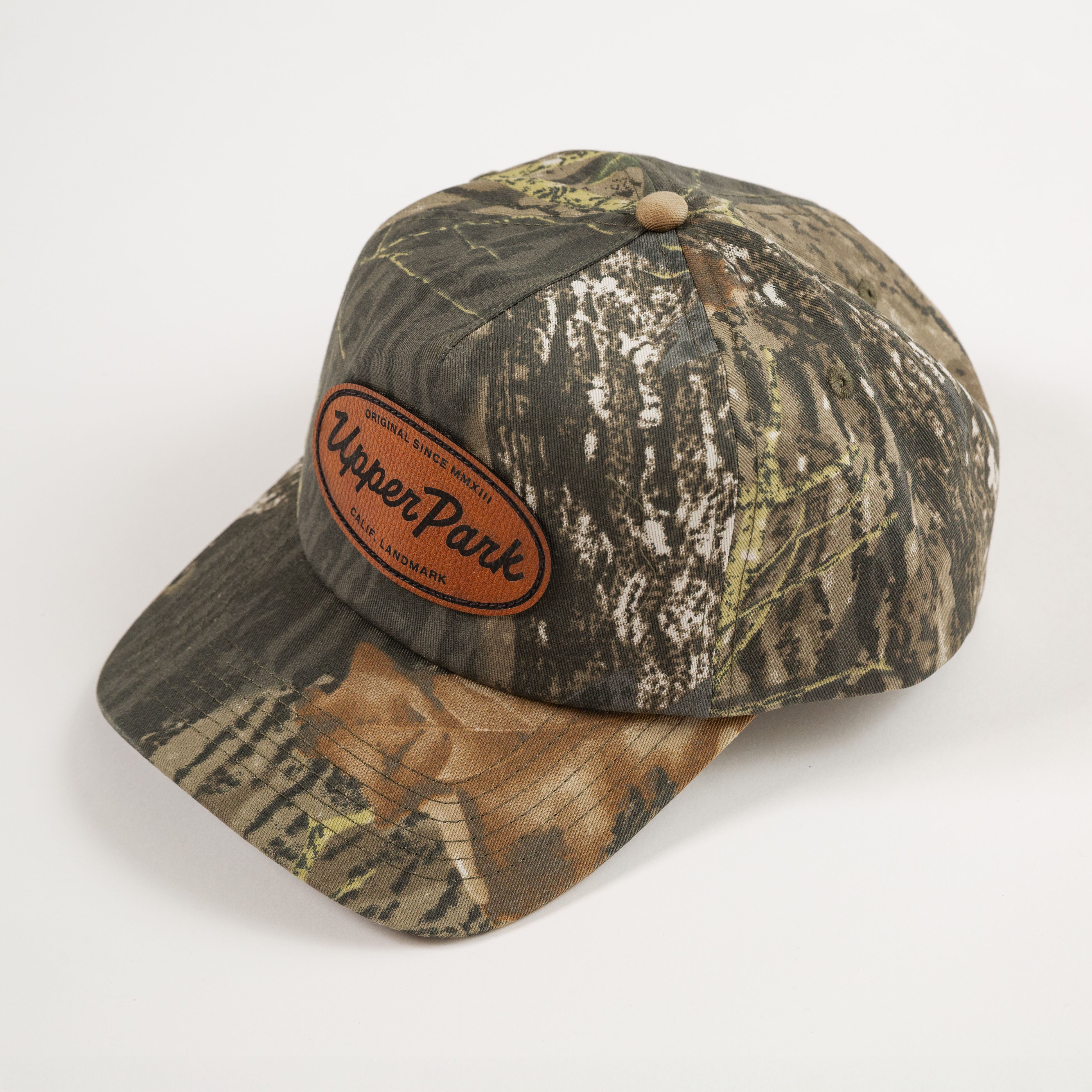 Camouflage baseball cap with a leather patch on a white background